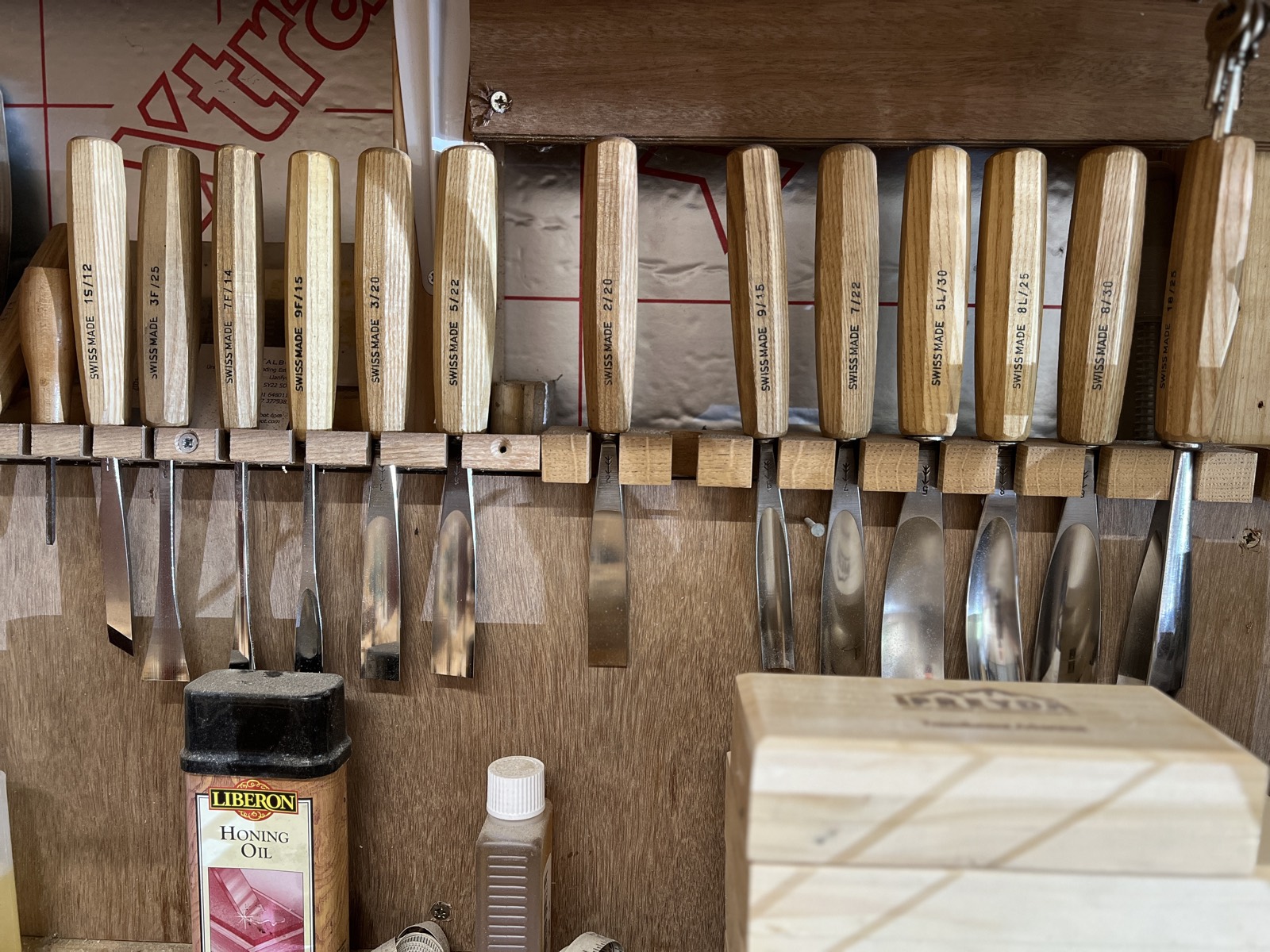 A rack of carving gouges above the bench, each blade hanging in its place